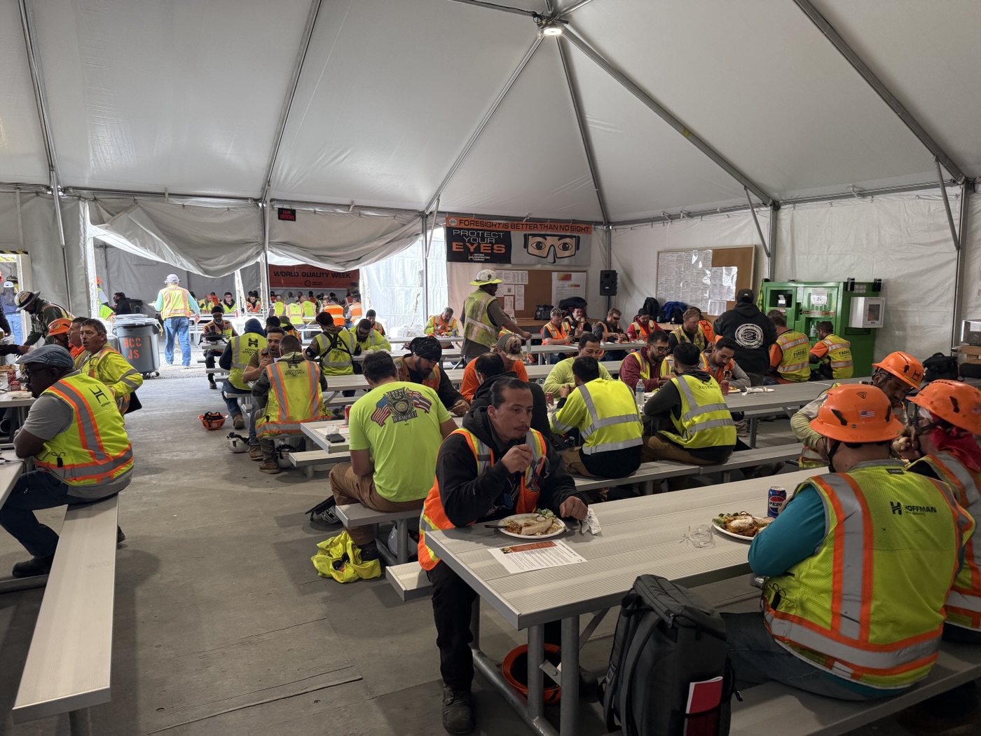 Construction crews gathering for a catered meal under an event tent