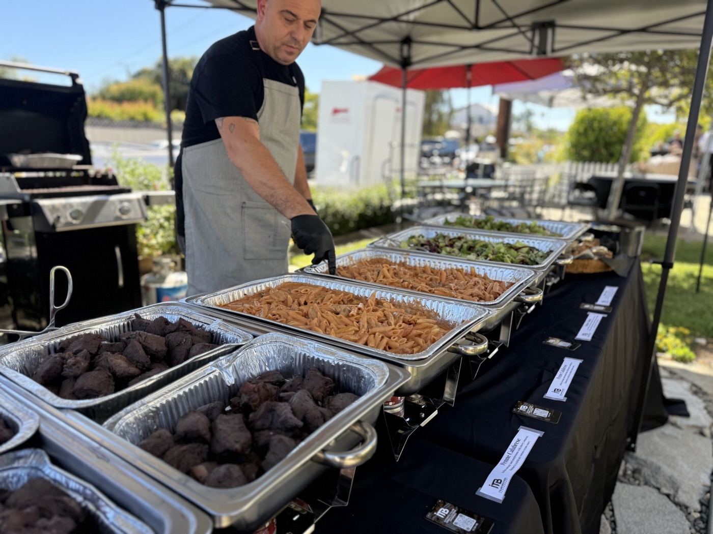 Italian Brothers team tending an outdoor buffet of pasta, meat and salads